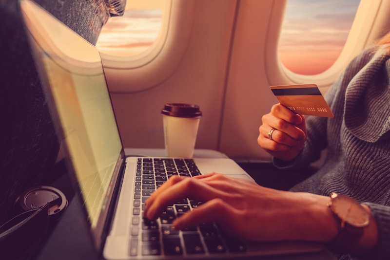 Woman in flight using her credit card to purchase online on her laptop