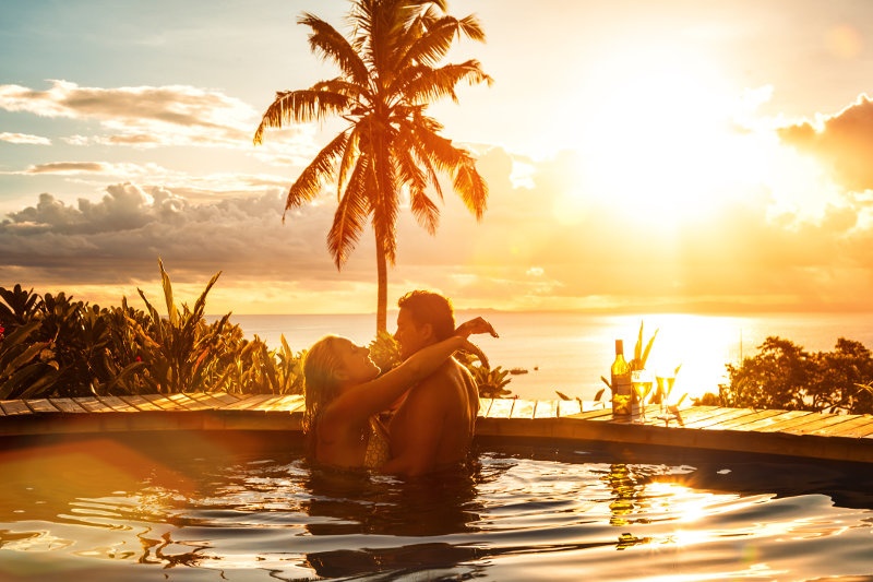 A couple in a pool with an ocean view at sunset in Fiji.