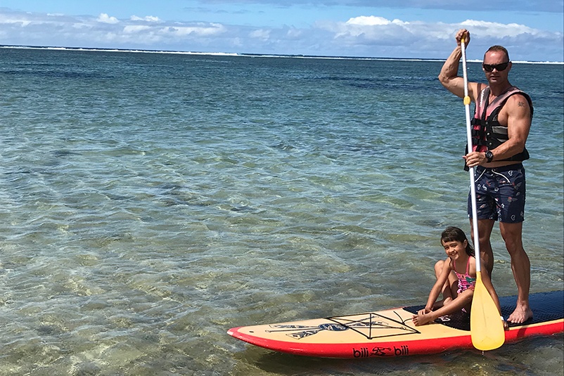 A father and daughter on a SUP board in Fiji