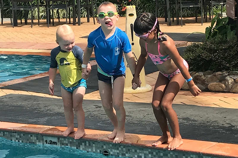 Three kids jump into a pool in Fiji