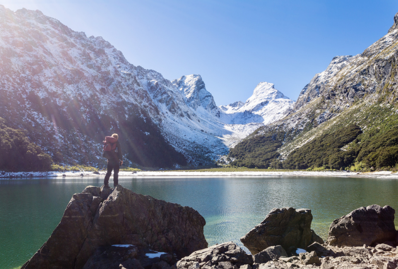 Man standing on a large rock admiring the mountain view 