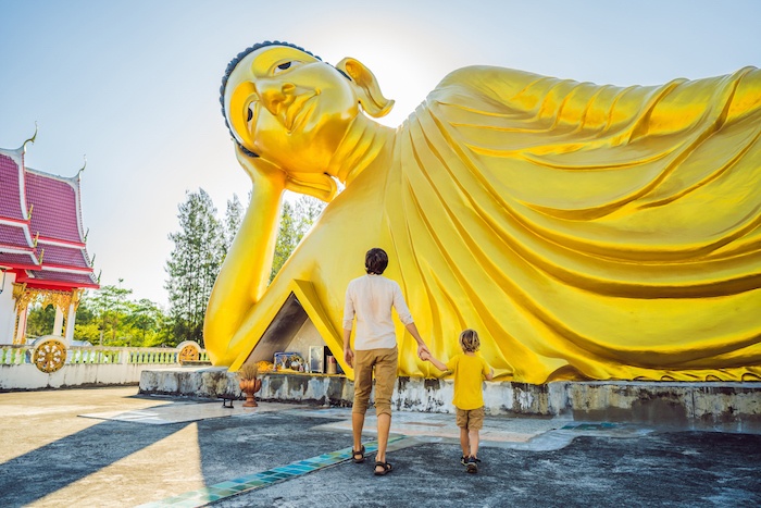 father and son admire large buddha in Thailand