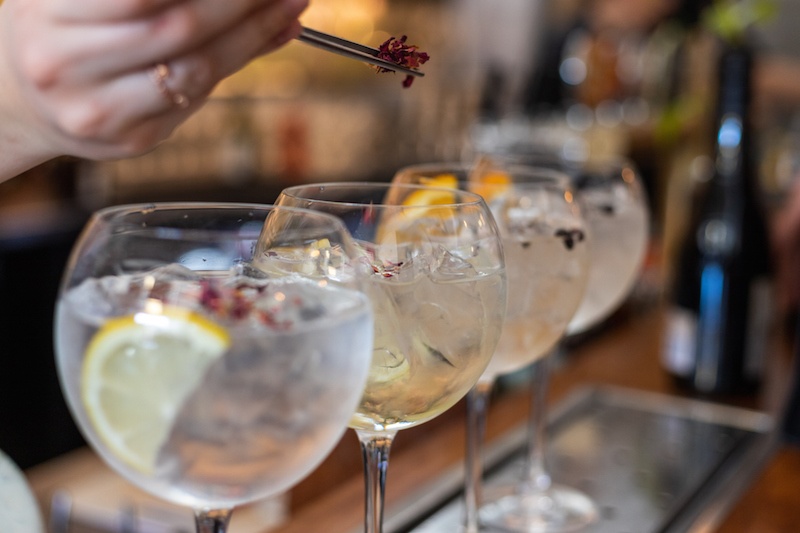 Four clear cocktails being garnished 