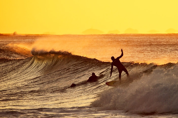 surfer riding wave newcastle nsw at sunrise