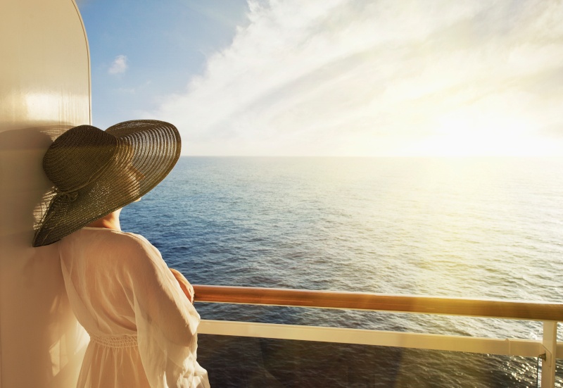 woman looking out to sea from her cabin. She is wearing a black hat