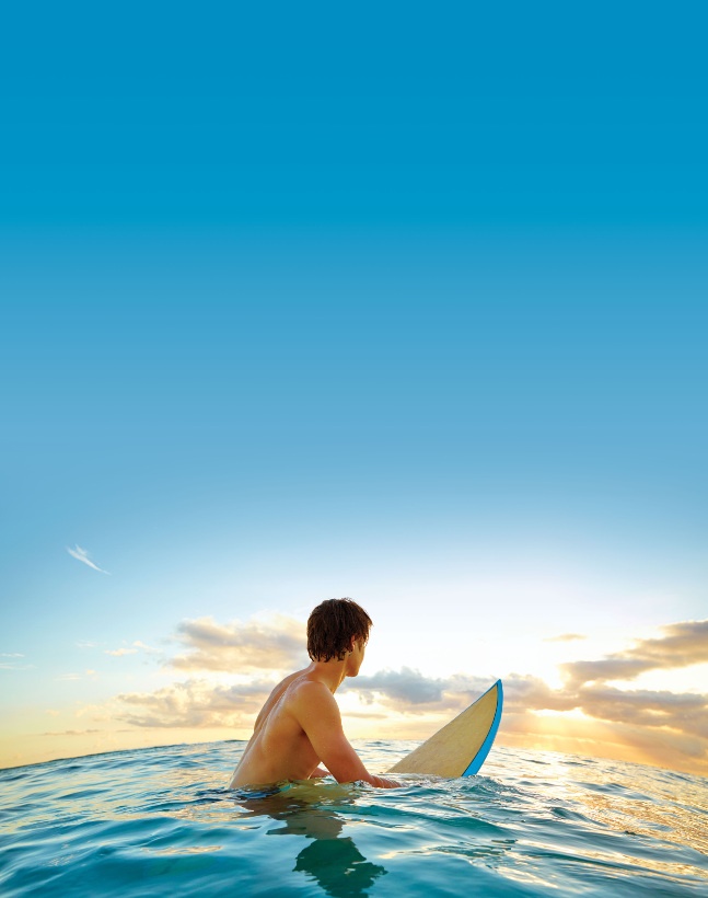 surfer sitting on board in water at sunrise