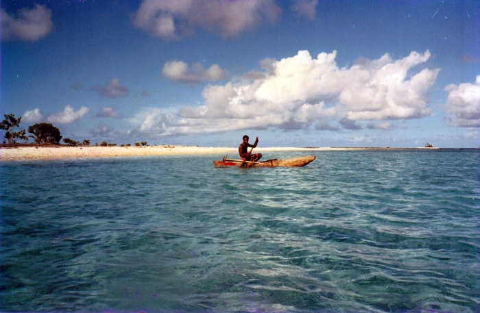 man in timber canoe papua new guinea