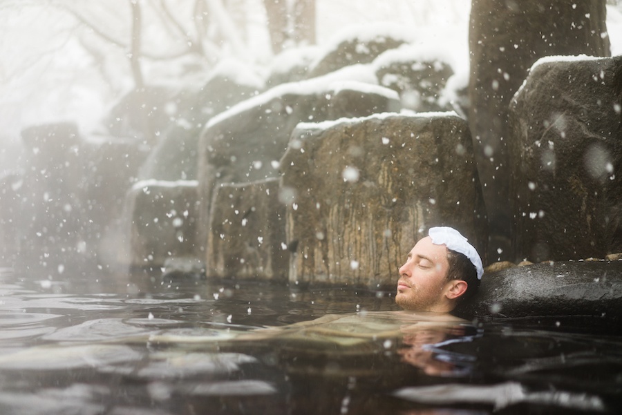 Man bathing in outdoor onsen in Japan in the snow