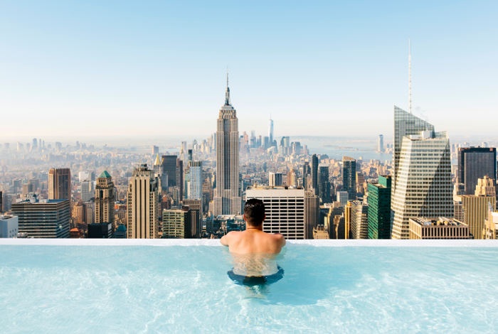 Man lounging on the edge of an infinity pool on top of a building