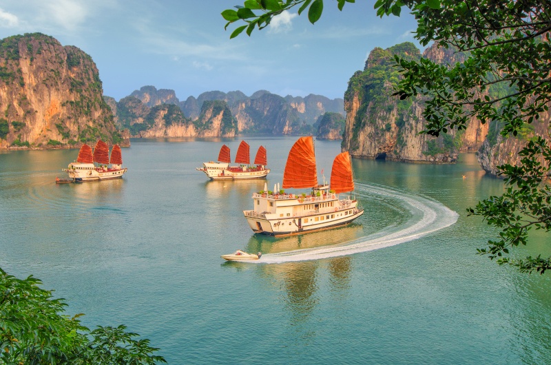 Three enormous ship and a small white boat sailing at Ha Long Bay