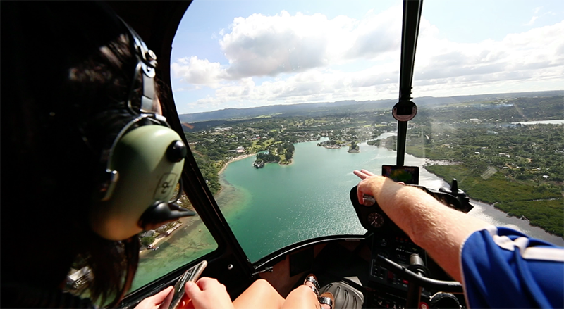 Helicopter pilot points to an island in the distance to the person beside him