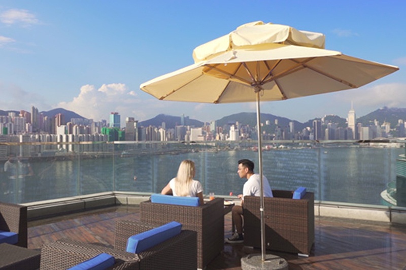 A man and a woman sit by the pool at a Hong Kong hotel.