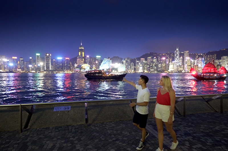 Two people walk along Tsim Sha Tsui Promenade in Kowloon, Hong Kong.