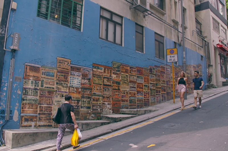 People walk past vibrant street art in Old Town Central, Hong Kong.