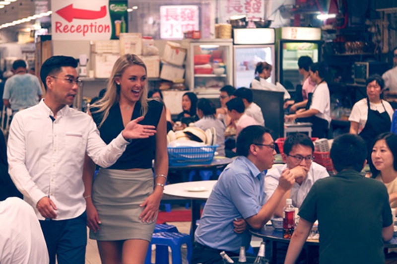 Two people walk through the bustling Tung Po food court in Hong Kong.