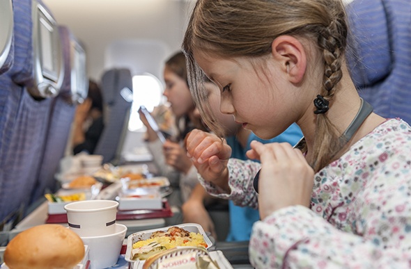 Three kids having dinner on the plane 