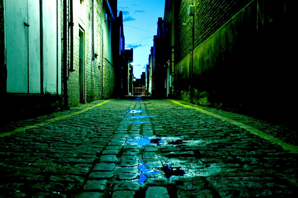 an alley way with puddles lit with green light