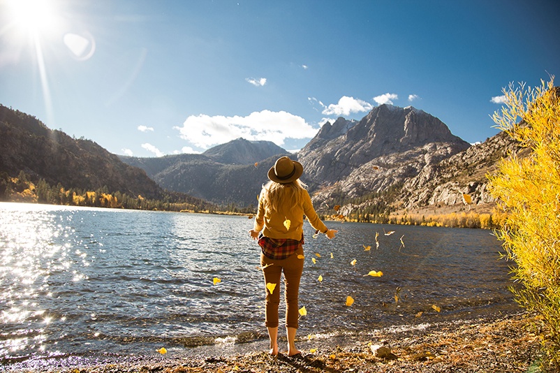 A woman stands on the shore amid autumn leaves at Silver Lake, California