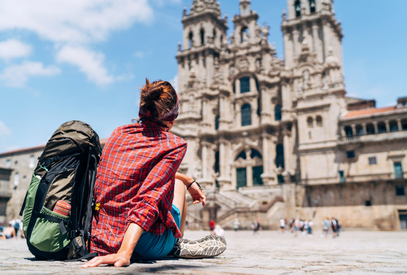 Woman backpacker piligrim siting on the Obradeiro square (plaza) in Santiago de Compostela