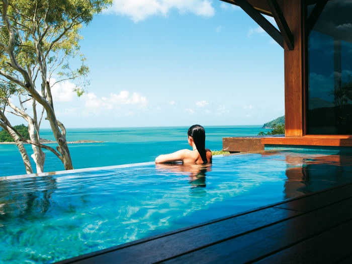 Woman swimming in pool and looking off to the ocean view 