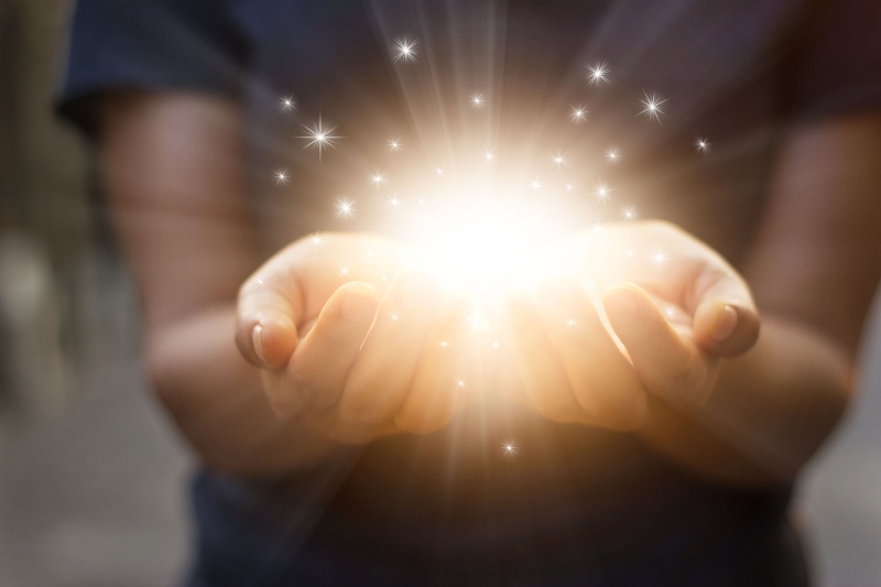 A woman holds lights and sparks in her hands.