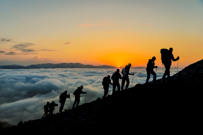 A row of mountain climbers scaling a peak.