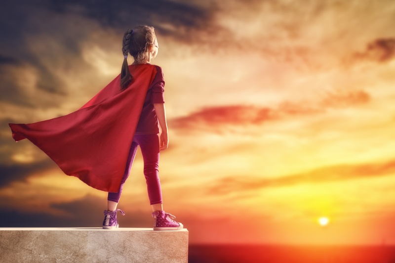 young girl looking at the sunset wearing red cape 