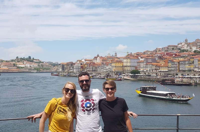 Three friends smiling at the camera with the colourful city of porto in the background