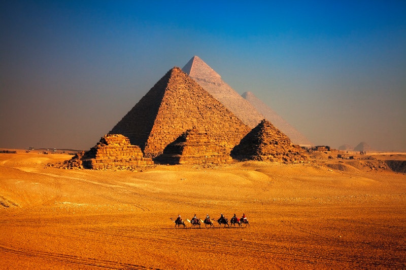 camel caravan in front of Egyptian pyramids