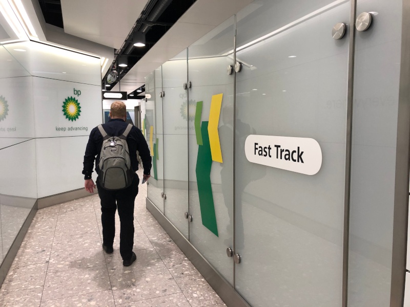 A man walking through an airport corridor with a sign that says fast track