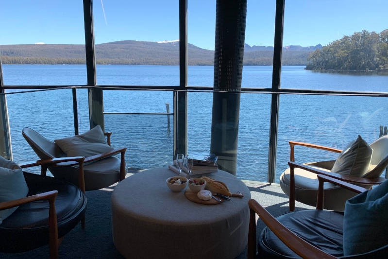 seats inside that look out over Lake St Clair. There is a cheese board and glasses of wine on a table