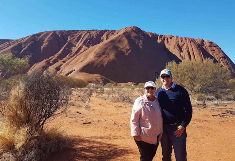Karen and Cameron standing in front of Uluru for a photo 