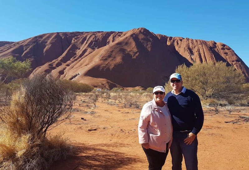 Karen and Cameron standing in front of Uluru for a photo