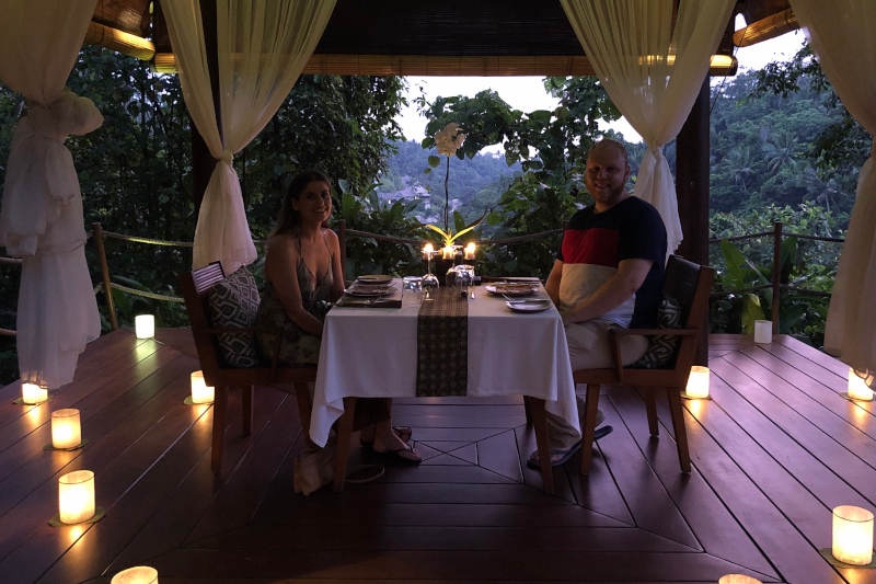 Sheridan and Damon sitting at a dinner table with candles surrounding them 