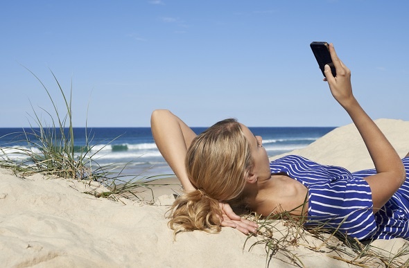 girl texting lying on beach