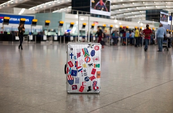 lone suitcase in airport with stickers on