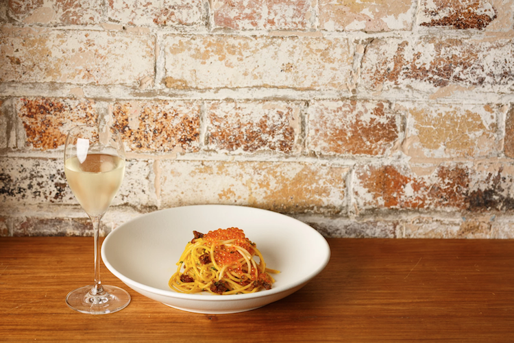 Siffredis pasta dish alongside a glass of white wine
