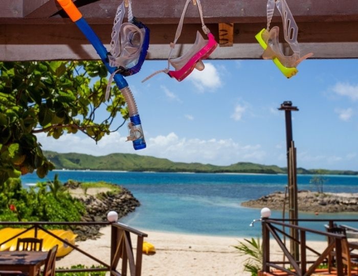 Snorkel gear hangs from roof of verada looking out towards ocean and small island