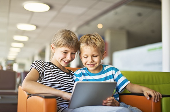 kids using their tablet in the airport lounge 