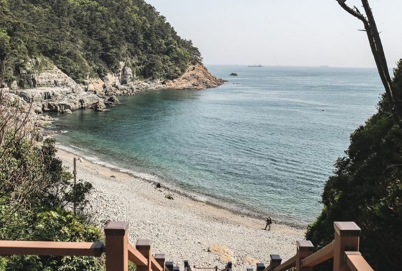 Looking down from top of wooden steps to blue water and rocky beach of Taejongdae Resort Park  