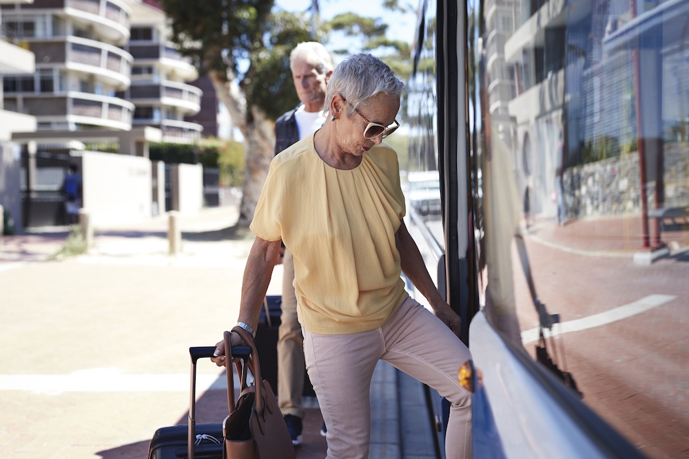 Couple carrying their suitcase outside the hotel boarding the bus