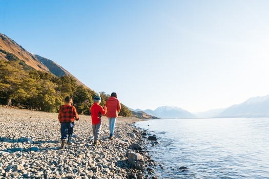 a mother and her two toddlers walking through the shore of Lake Ohau in New Zealand