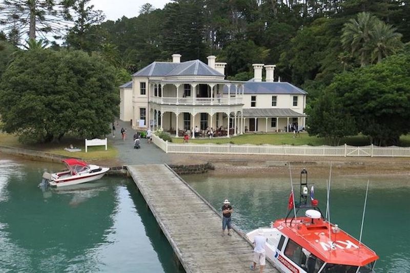A drone's view of the jetty, moored boats and a colonial mansion on the shore of Kawau Island in the Hauraki Gulf
