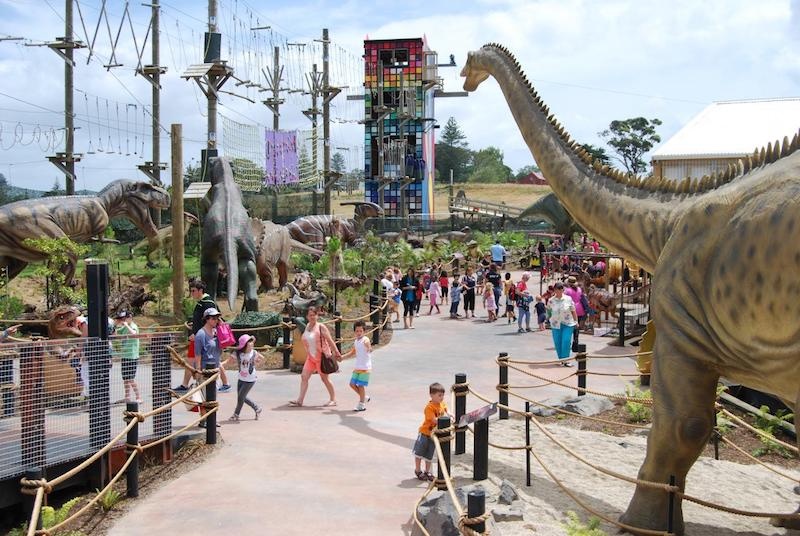 People walk among life-sized models of dinosaurs at Butterfly Creek themepark, Auckland