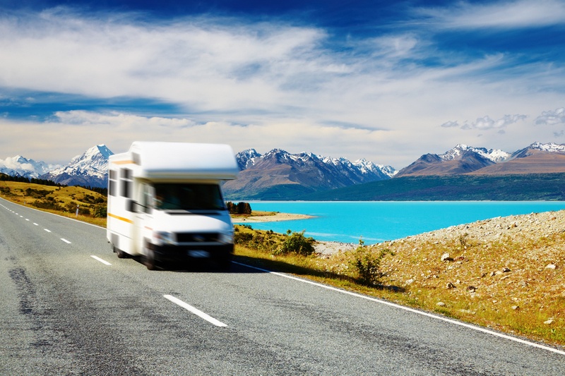 Campervan driving by Lake Pukaki with Mount Cook in the background, New Zealand.