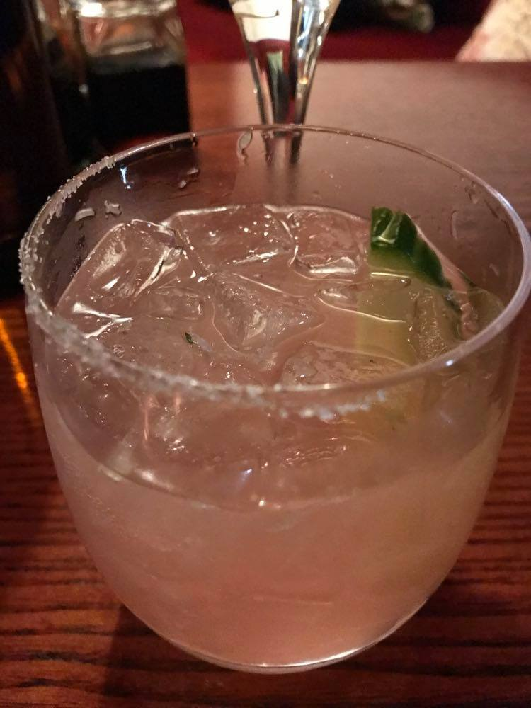 A pink cocktail with plenty of ice and a slice of lime.