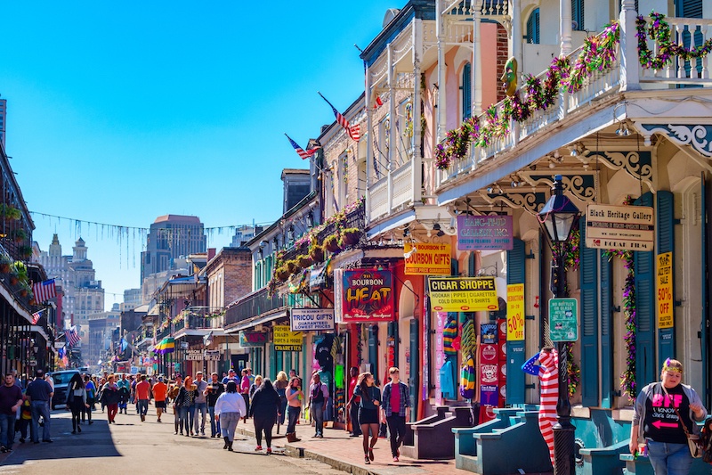 Street in New Orleans decorated for Mardi Gras with people walking along