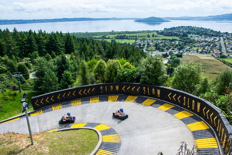 A sharp bend in the Skyline Luge with forest and Lake Rotorua in the background.