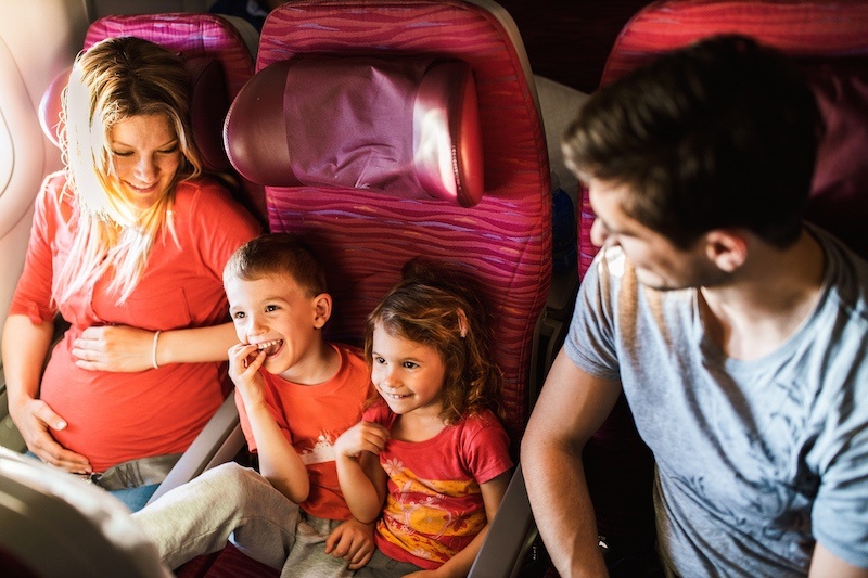 Family sitting in plane, two kids sharing seat between parents