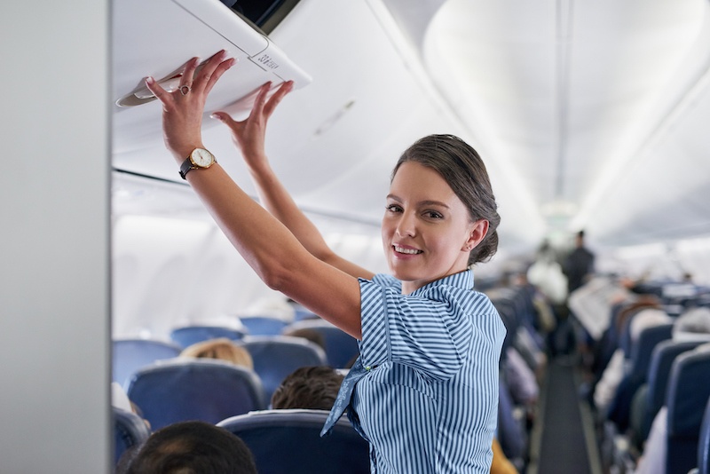 air hostess closing overhead locker on plane